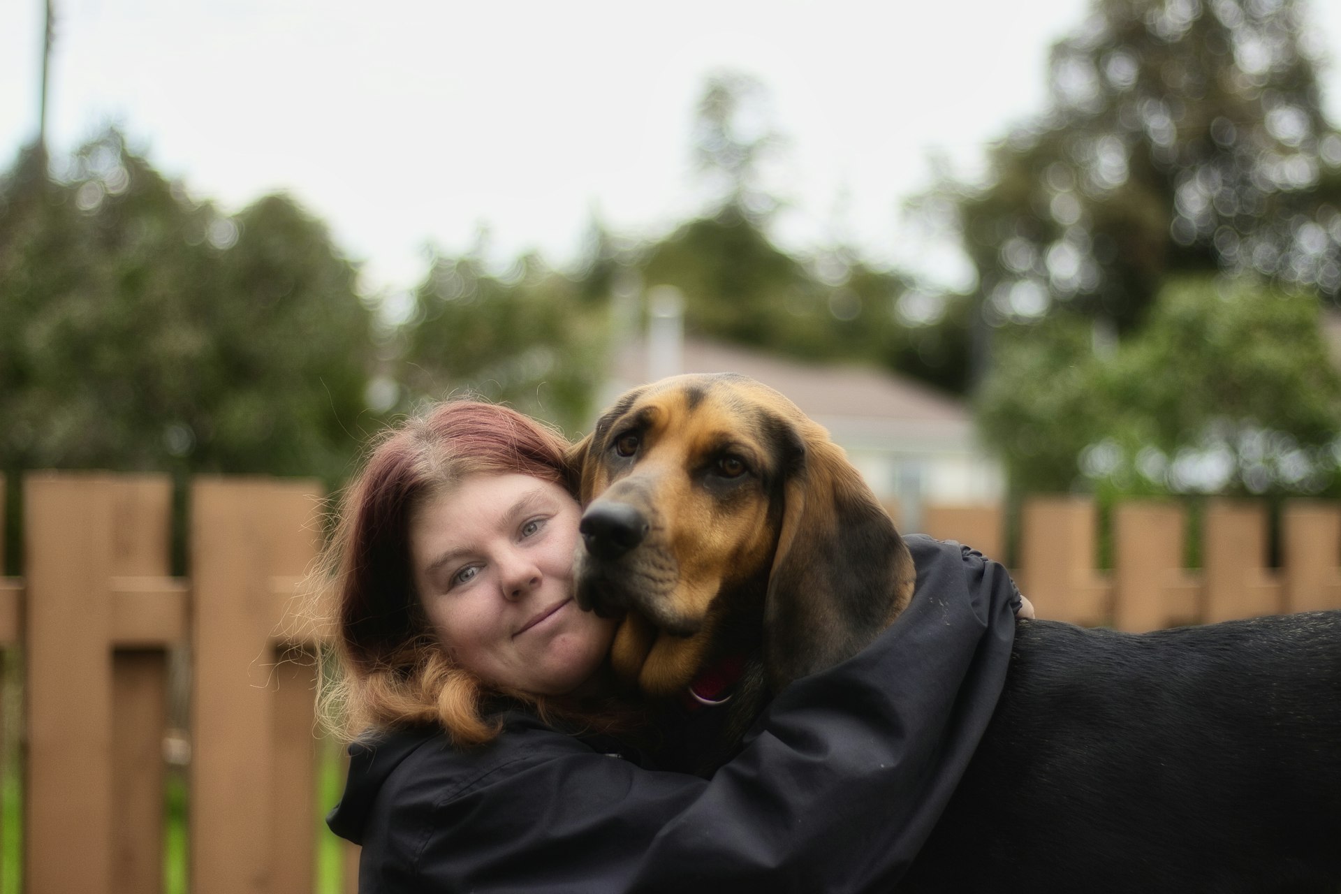 A woman crouching beside her beagle on a country path